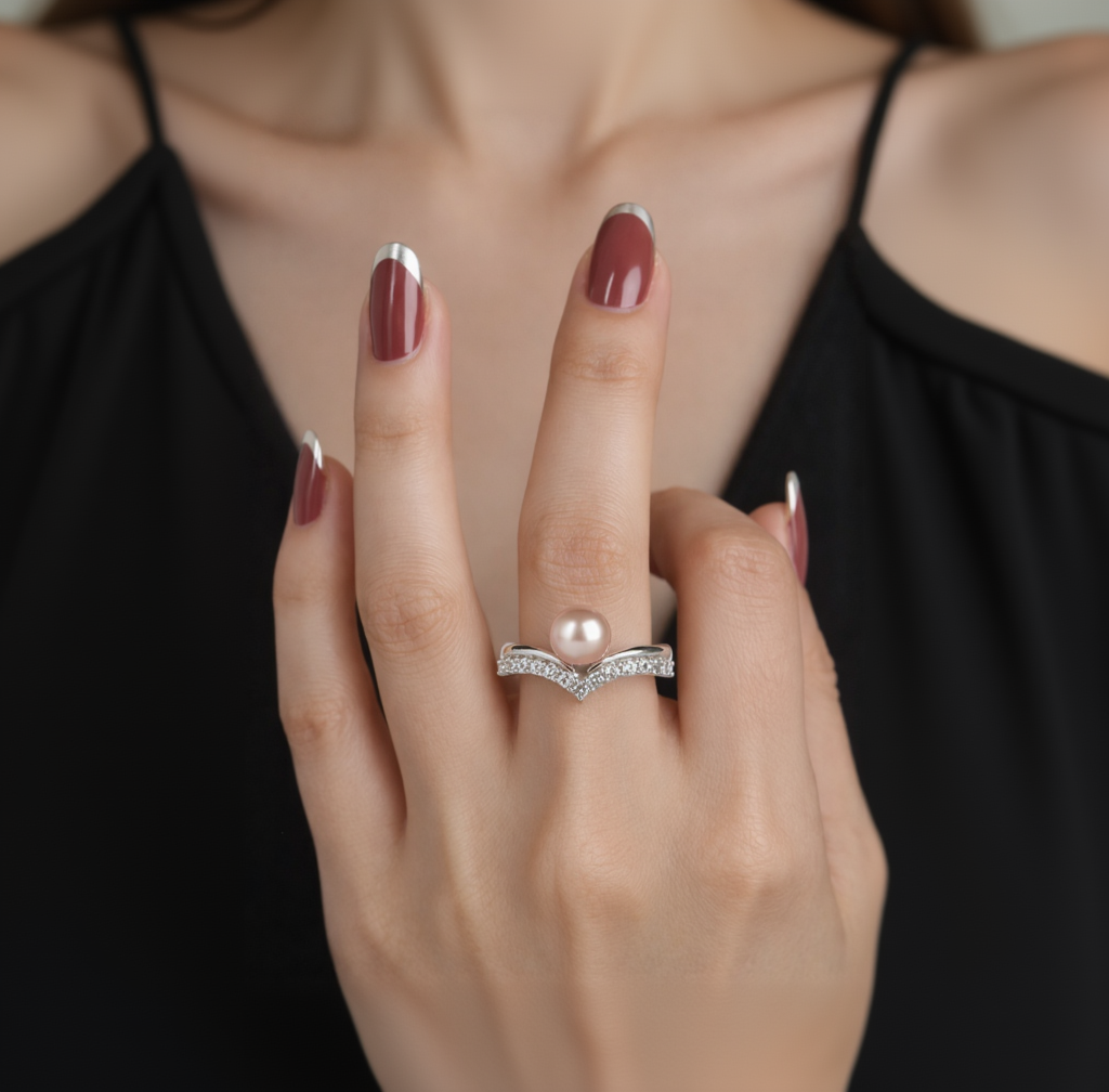Close-up of a hand wearing a pearl and diamond ring against a dark background