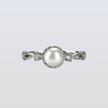 Pearl ring with silver band on a light gray background