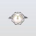 Pearl ring with silver floral design on a light gray background