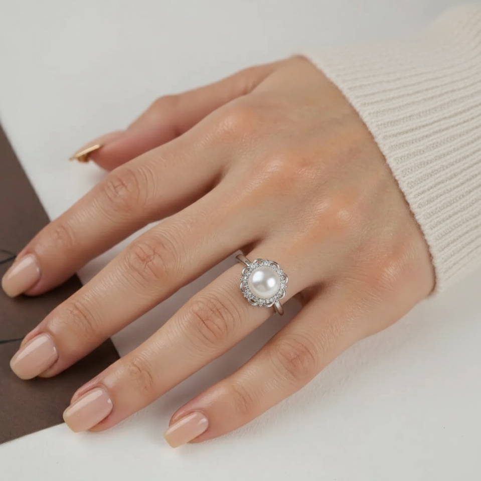 Hand wearing a pearl ring on a neutral background