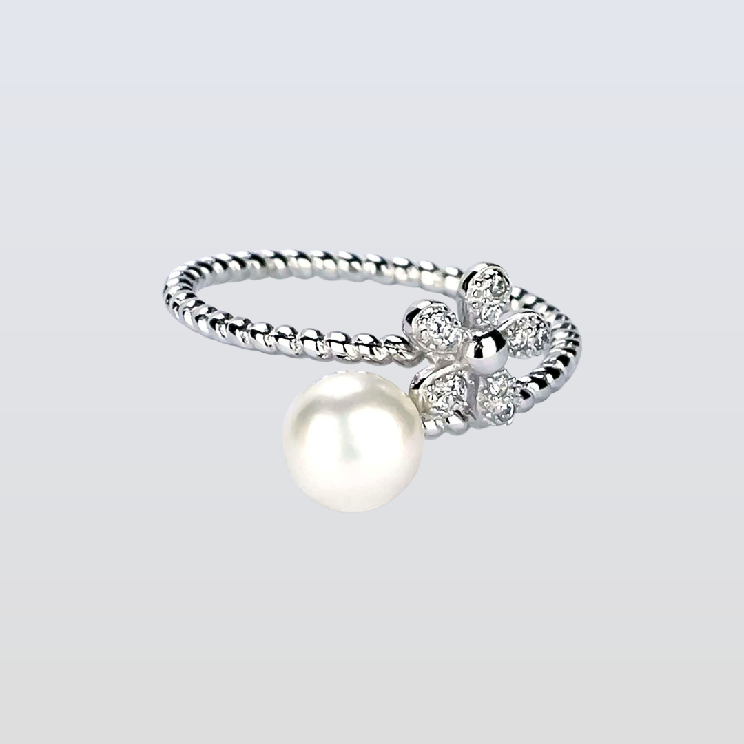 Silver ring with a pearl and small diamonds on a light gray background