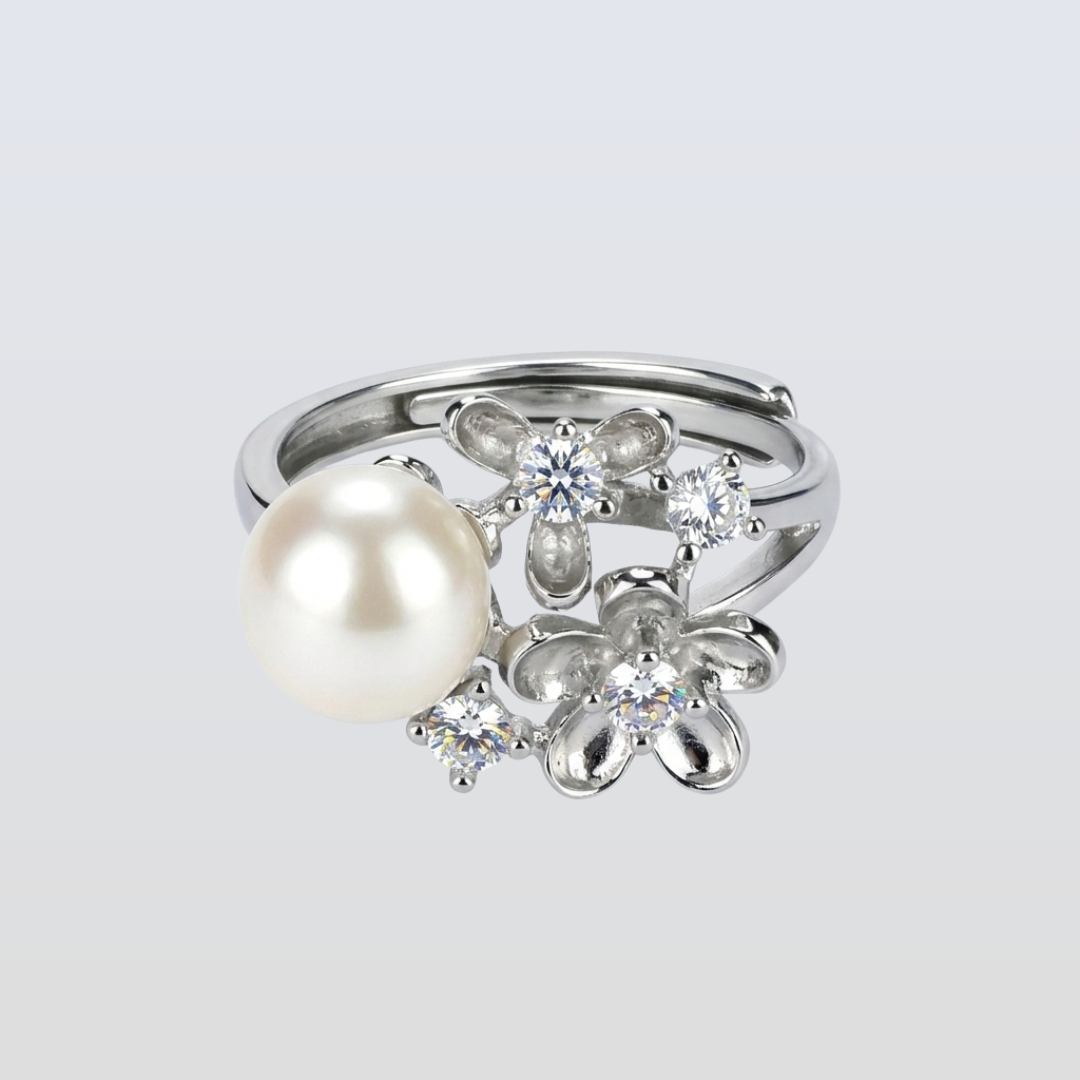 Silver ring with a pearl and floral diamond design on a light gray background