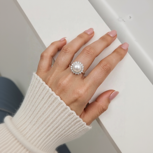 Hand wearing a pearl ring on a white background
