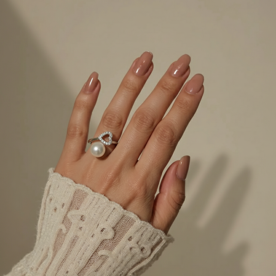 Hand wearing a pearl ring on a neutral background