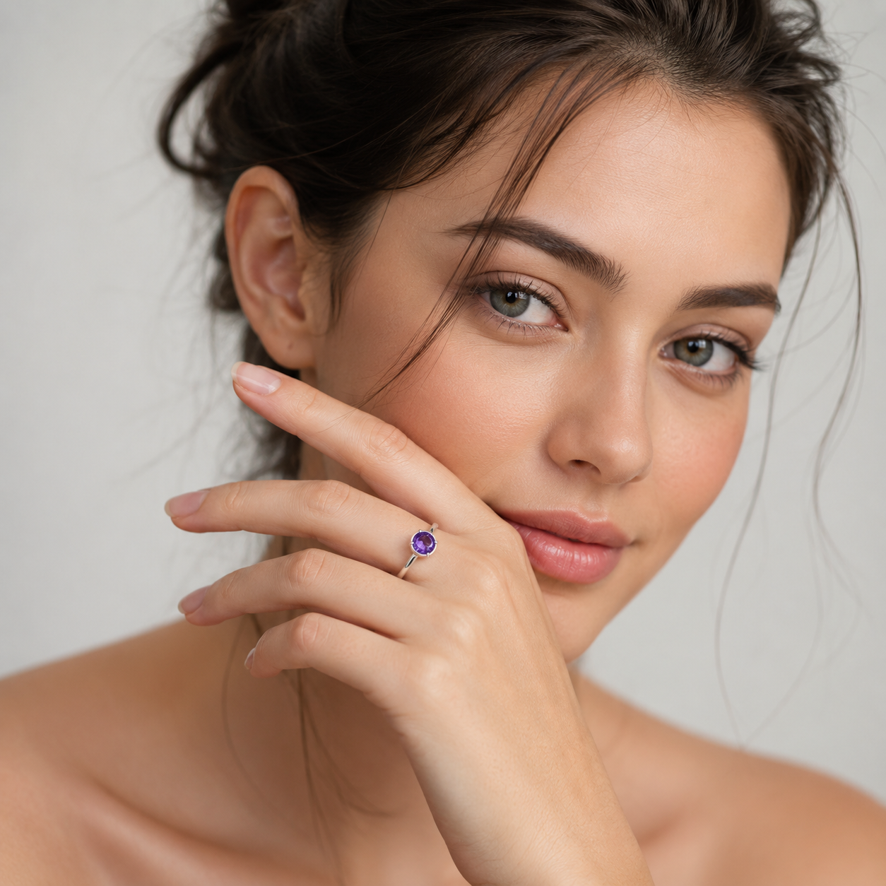 Woman wearing a purple gemstone earring against a neutral background