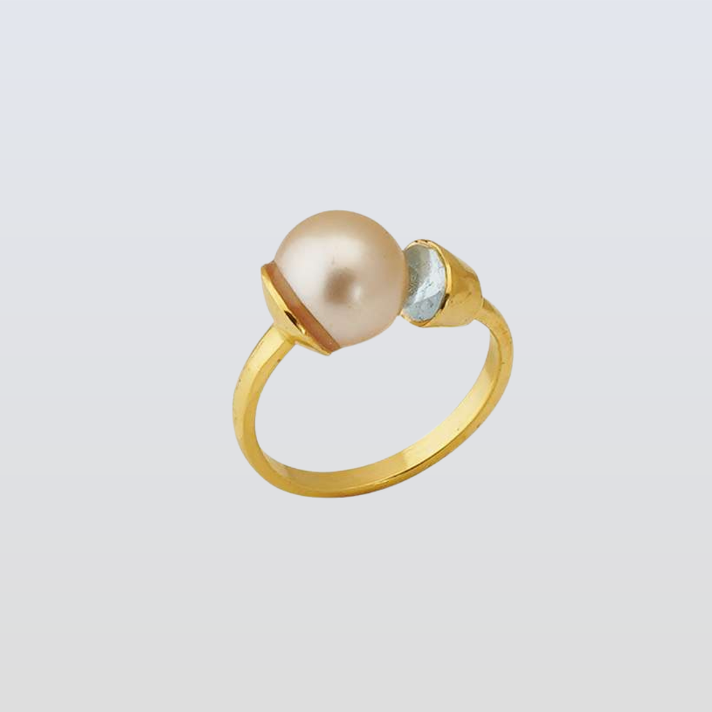 Gold ring with a pearl and small gemstone on a light gray background