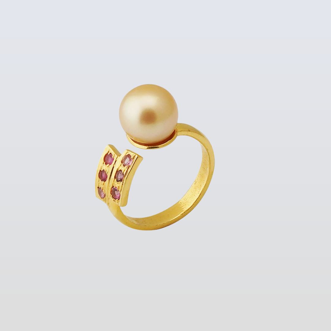 Gold ring with a pearl and pink gemstones on a light gray background