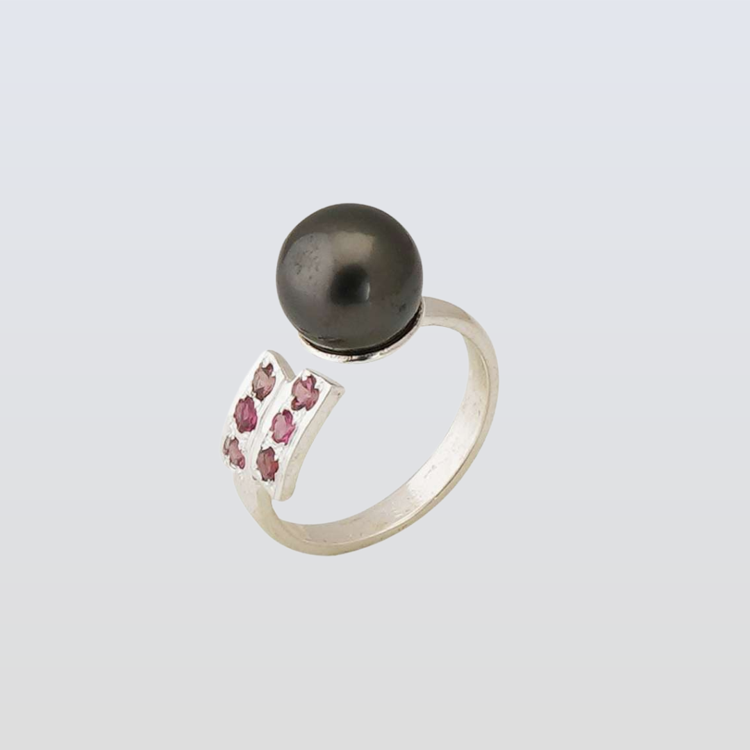 Silver ring with a black pearl and pink gemstones on a light gray background