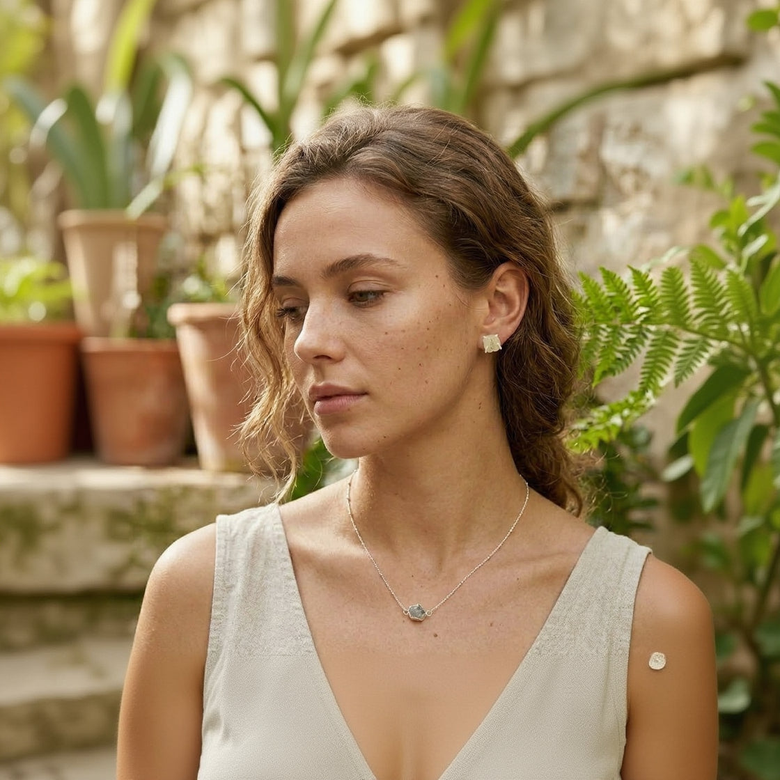 Woman wearing a necklace with plants in the background