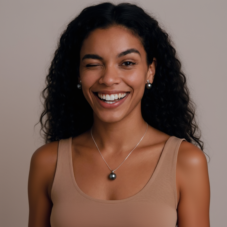 Woman wearing a necklace with a dark pendant against a neutral background