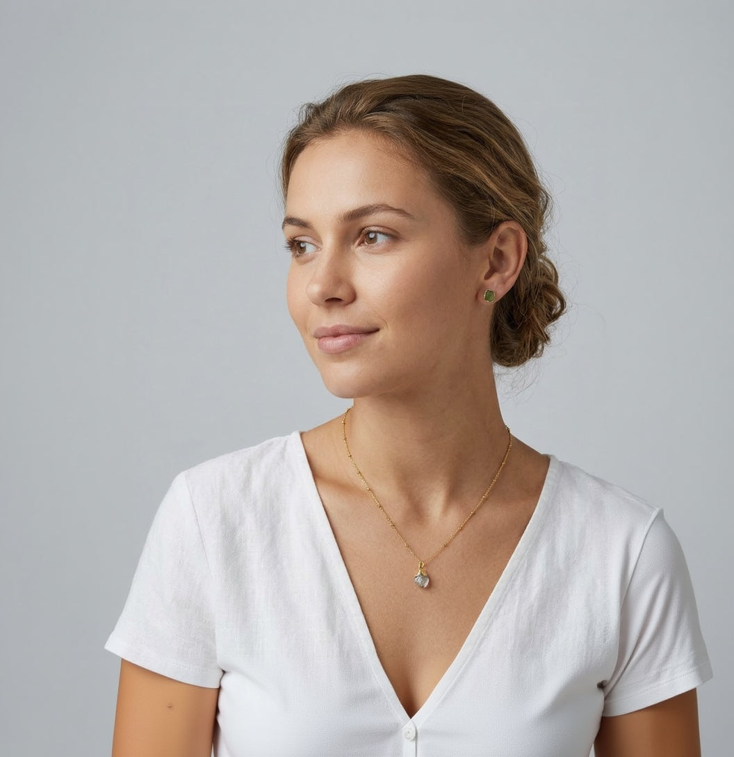 Woman wearing a gold necklace and earrings against a gray background