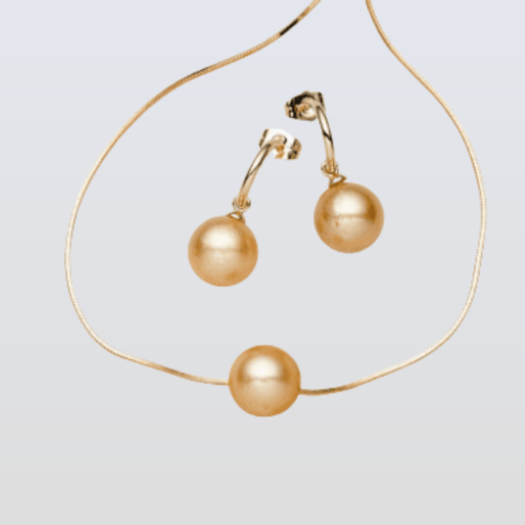 Gold pearl necklace and earrings on a light gray background