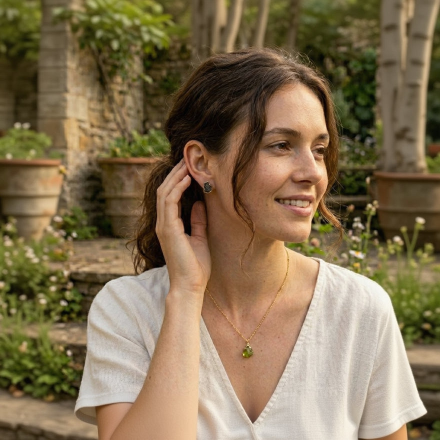 Woman wearing a necklace with a green pendant in a garden setting