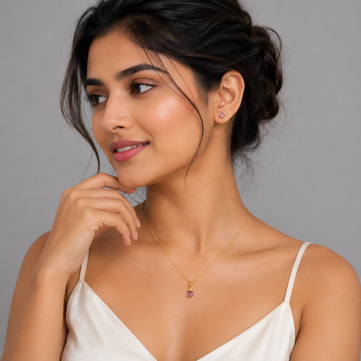 Woman wearing a necklace with a pendant against a gray background