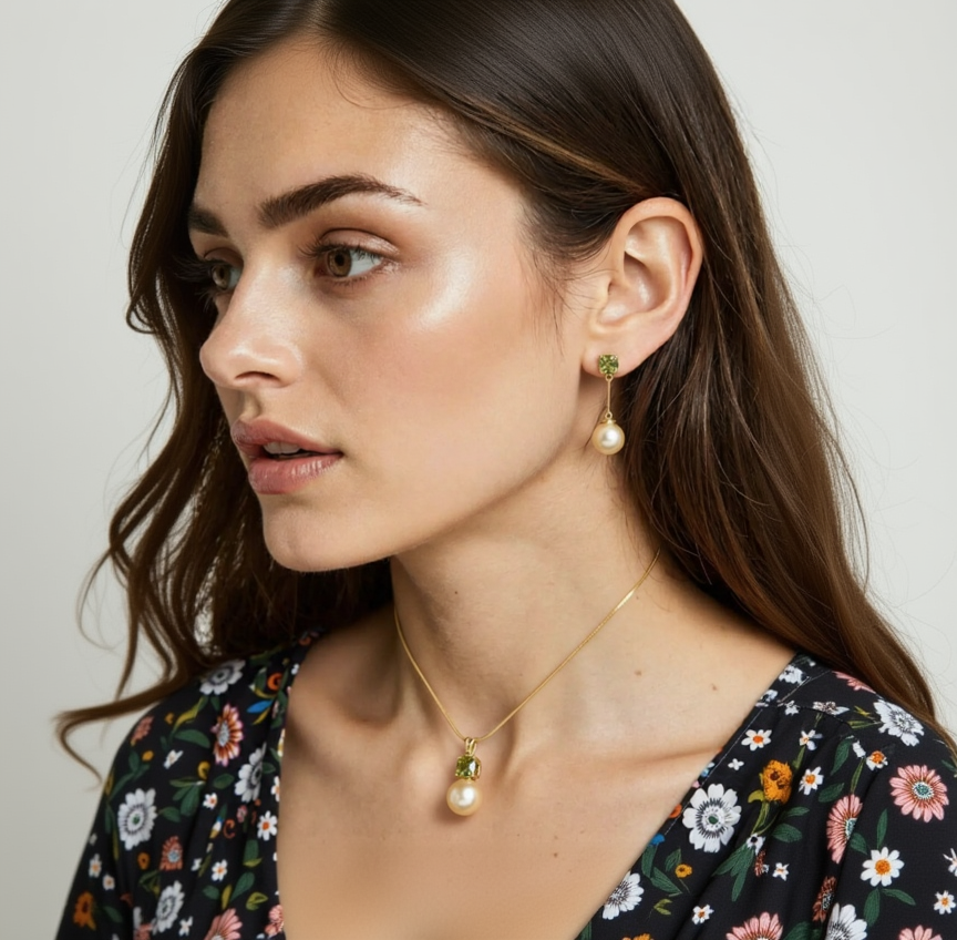 Close-up of a woman wearing pearl earrings and a gold necklace with a pendant.