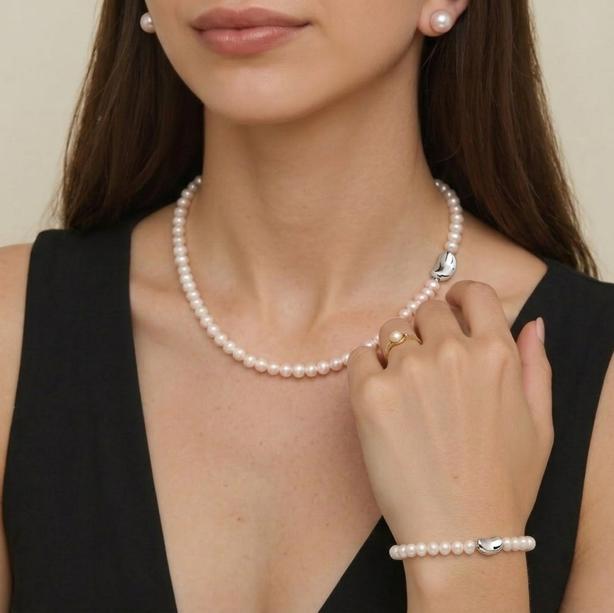 Woman wearing a pearl necklace and bracelet on a beige background