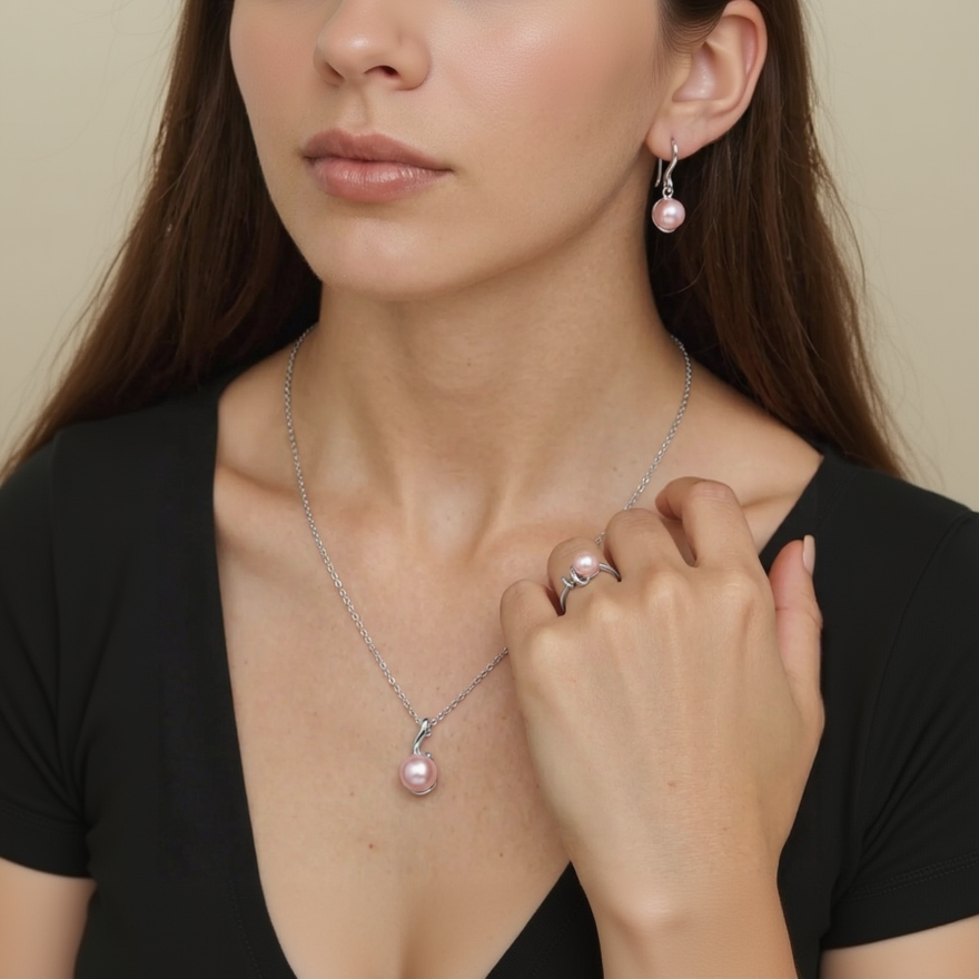 Woman wearing a silver necklace with a pink pearl pendant and matching earrings.