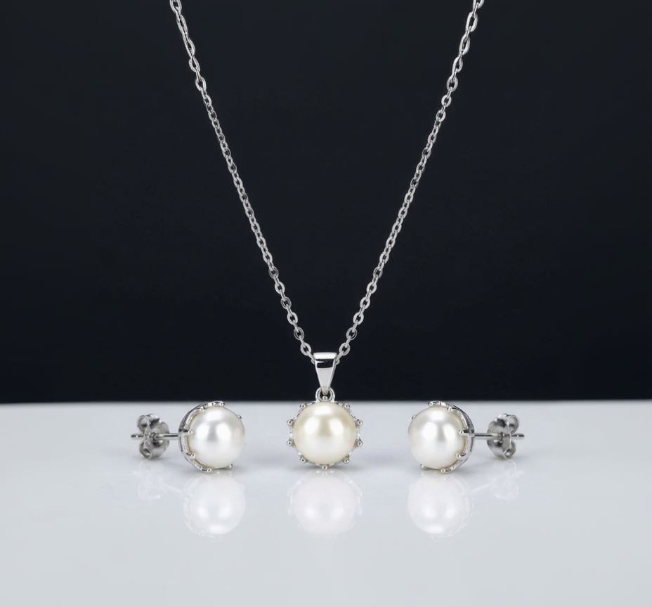 Pearl necklace and earrings set on a reflective surface with a black background
