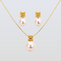 Pearl necklace and earrings set with gold accents on a light gray background