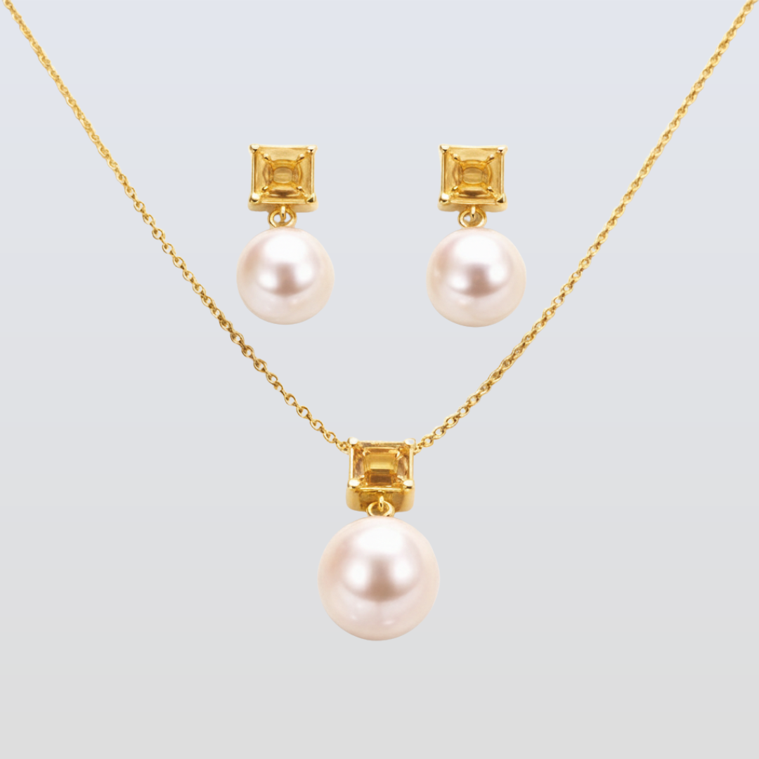 Pearl necklace and earrings set with gold accents on a light gray background