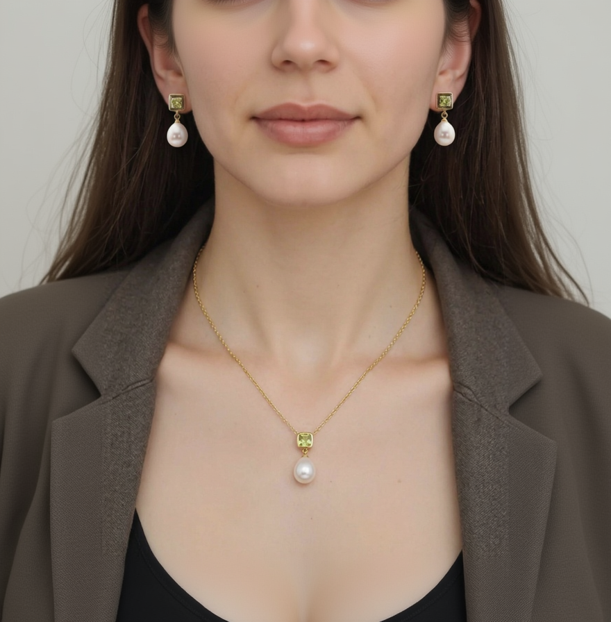 Close-up of a woman wearing a gold necklace with a pearl pendant and matching earrings.
