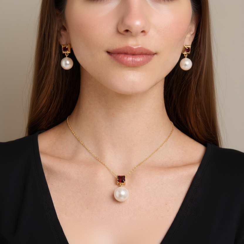 Close-up of a woman wearing a gold necklace with a pearl pendant and matching earrings.