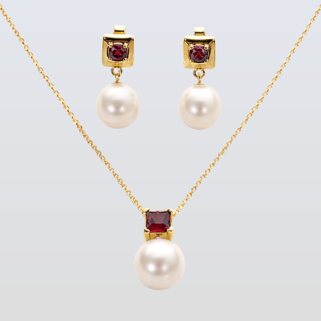 Pearl necklace and earrings with red gemstones on a light gray background