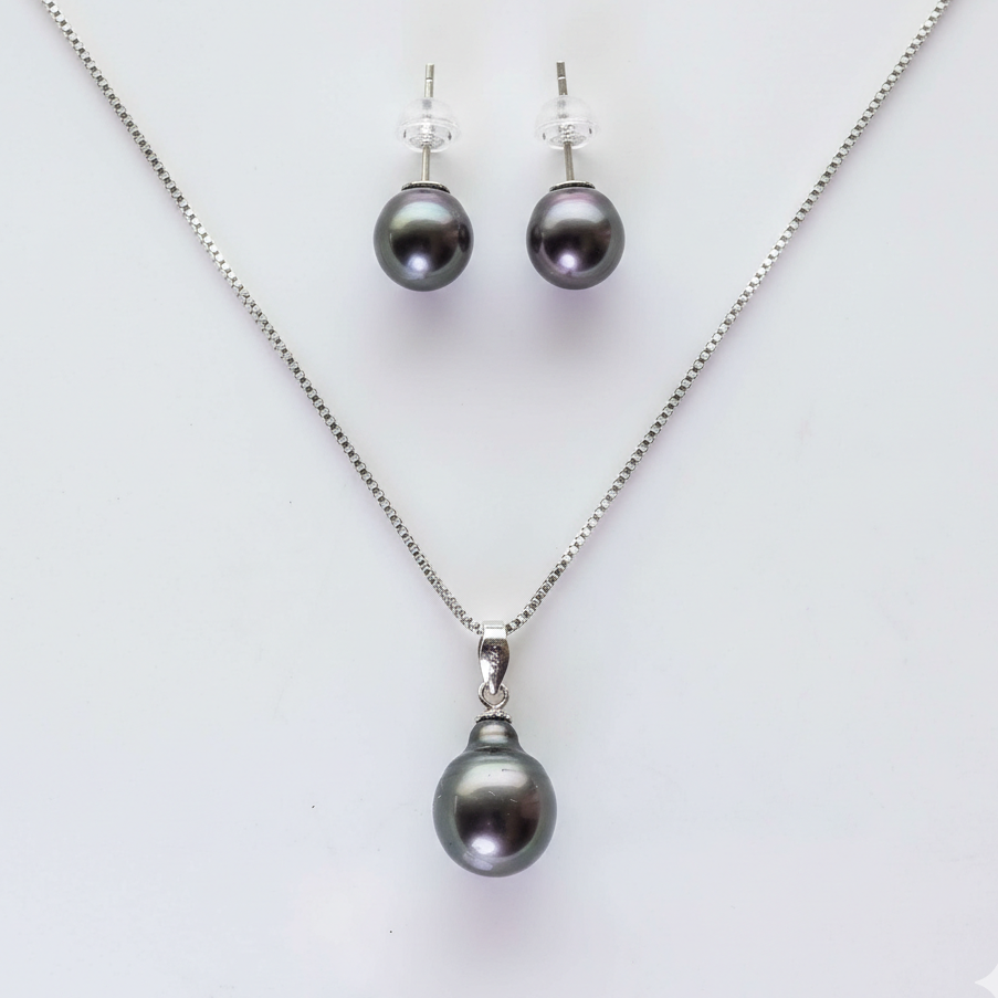 Pearl necklace and earrings set on a light gray background