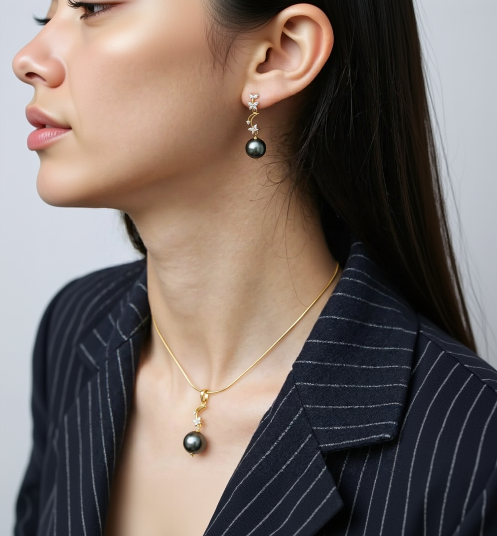 Close-up of a person wearing black pearl earrings and a matching necklace.