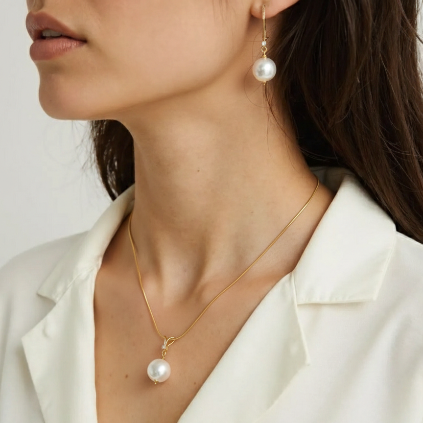 Pearl necklace and earrings on a person wearing a white blazer.
