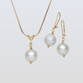 Pearl necklace and earrings set on a light gray background