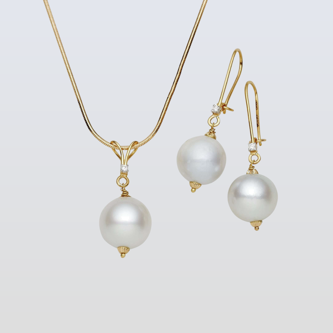 Pearl necklace and earrings set on a light gray background