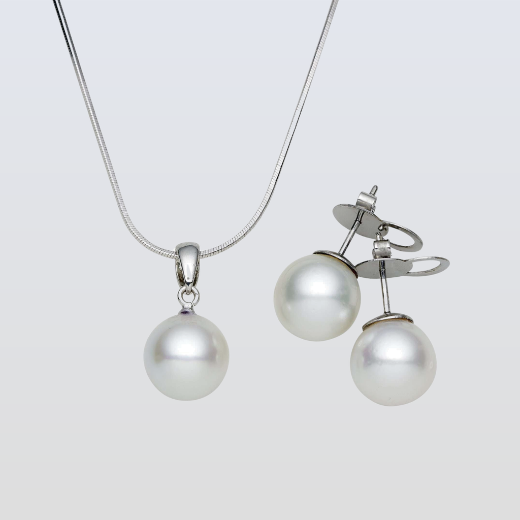 Pearl necklace and earrings set on a light gray background