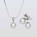 Pearl necklace and earrings set on a light gray background