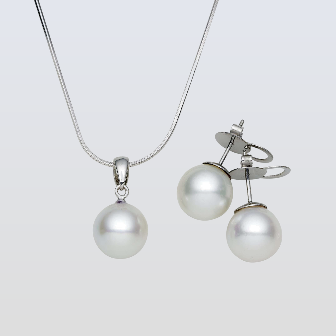 Pearl necklace and earrings set on a light gray background