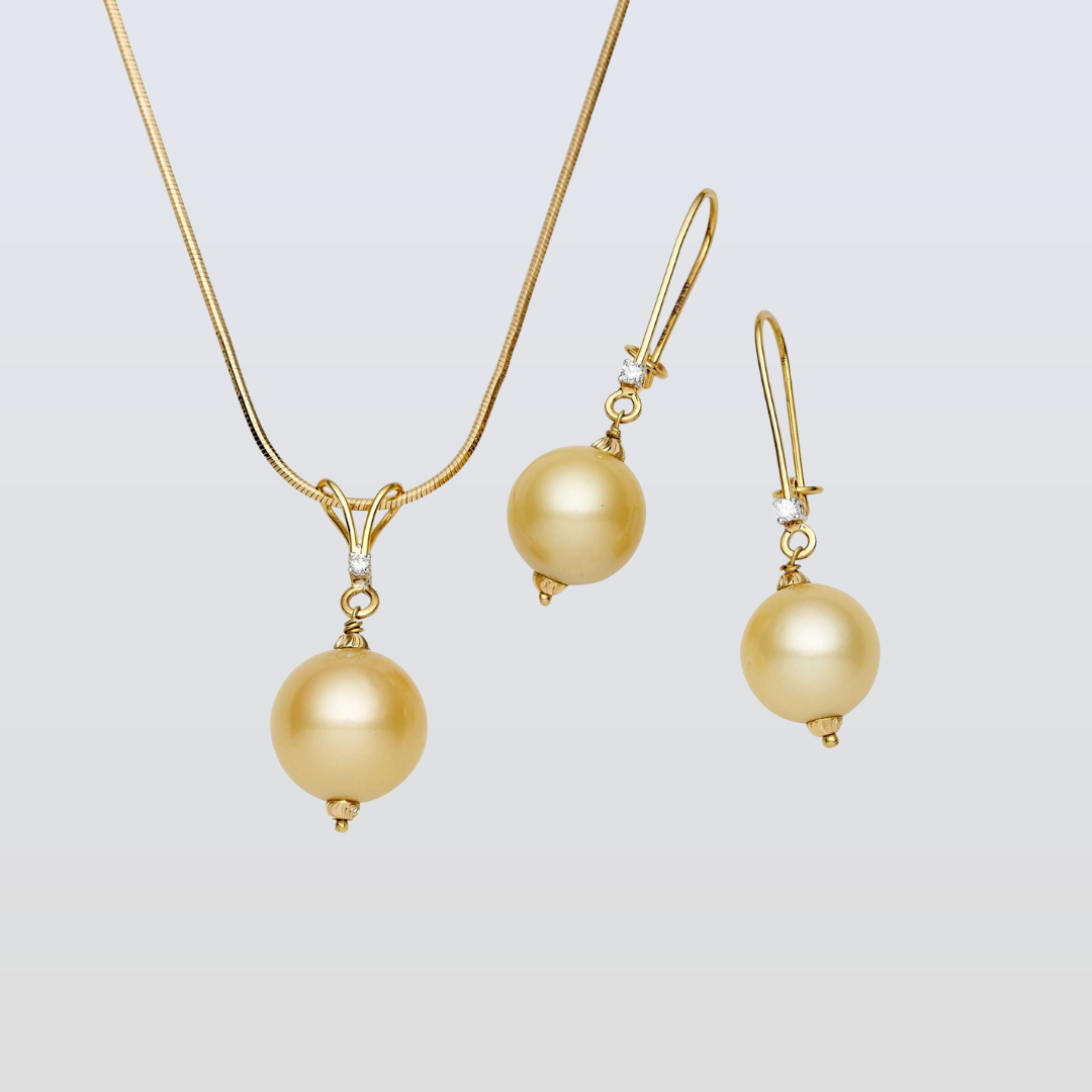 Gold necklace and earrings with pearl-like beads on a light gray background